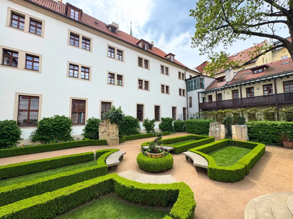 Augustine a Luxury Collection Hotel Prague | Venclikovi.com Peaceful monastery garden at Augustine Hotel Prague with manicured hedges and historic stone details.