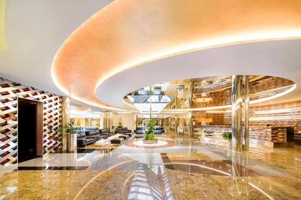 Grandium Hotel Prague | Venclikovi.com Grandium Hotel Prague lobby with modern curved ceiling design and golden marble floors.
