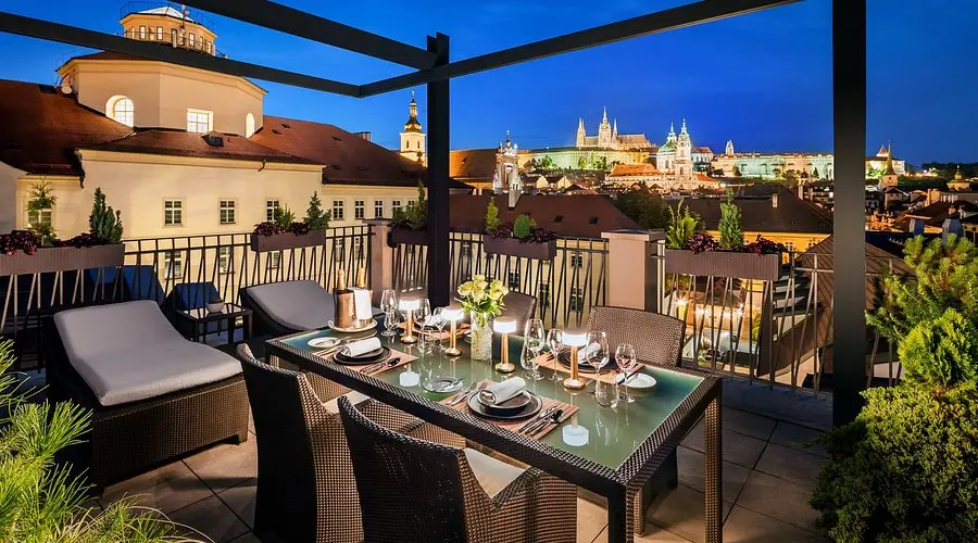 Mandarin Oriental Prague | Venclikovi.com Rooftop terrace at Mandarin Oriental Prague with dining table and panoramic night view of Prague Castle.
