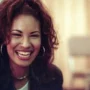 Selena Quintanilla smiling during a candid backstage moment, showing her natural charm and iconic style loved by fans around the world.