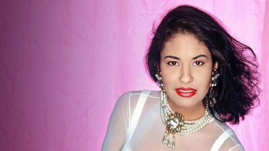 Selena Quintanilla close-up portrait with bold red lipstick and statement jewelry, set against a pink background—timeless beauty and confidence.