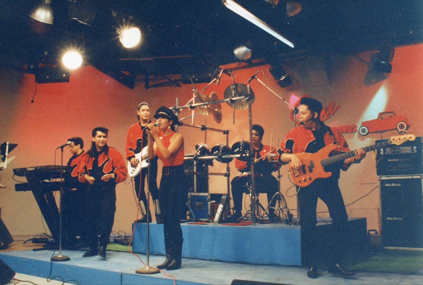 selena-y-los-dinos-tv-performance-red-outfits | Venclikovi.com Selena y Los Dinos performing live on television in matching red-and-black outfits, showcasing their early Tejano roots and family chemistry on stage.