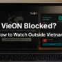 A dual-screen laptop showing VieON’s geo-block error on the left and NordVPN connected to a Ho Chi Minh City server on the right, with the title “VieON Blocked? How to Watch Outside Vietnam” in the center