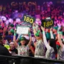 Darts fans in festive costumes holding “180” signs and cheering during the December 12 session at the 2025/26 World Darts Championship in Alexandra Palace.