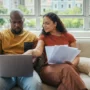 Couple checking their Chase bank account on a laptop while traveling, highlighting the risk of account access issues abroad without a US VPN connection