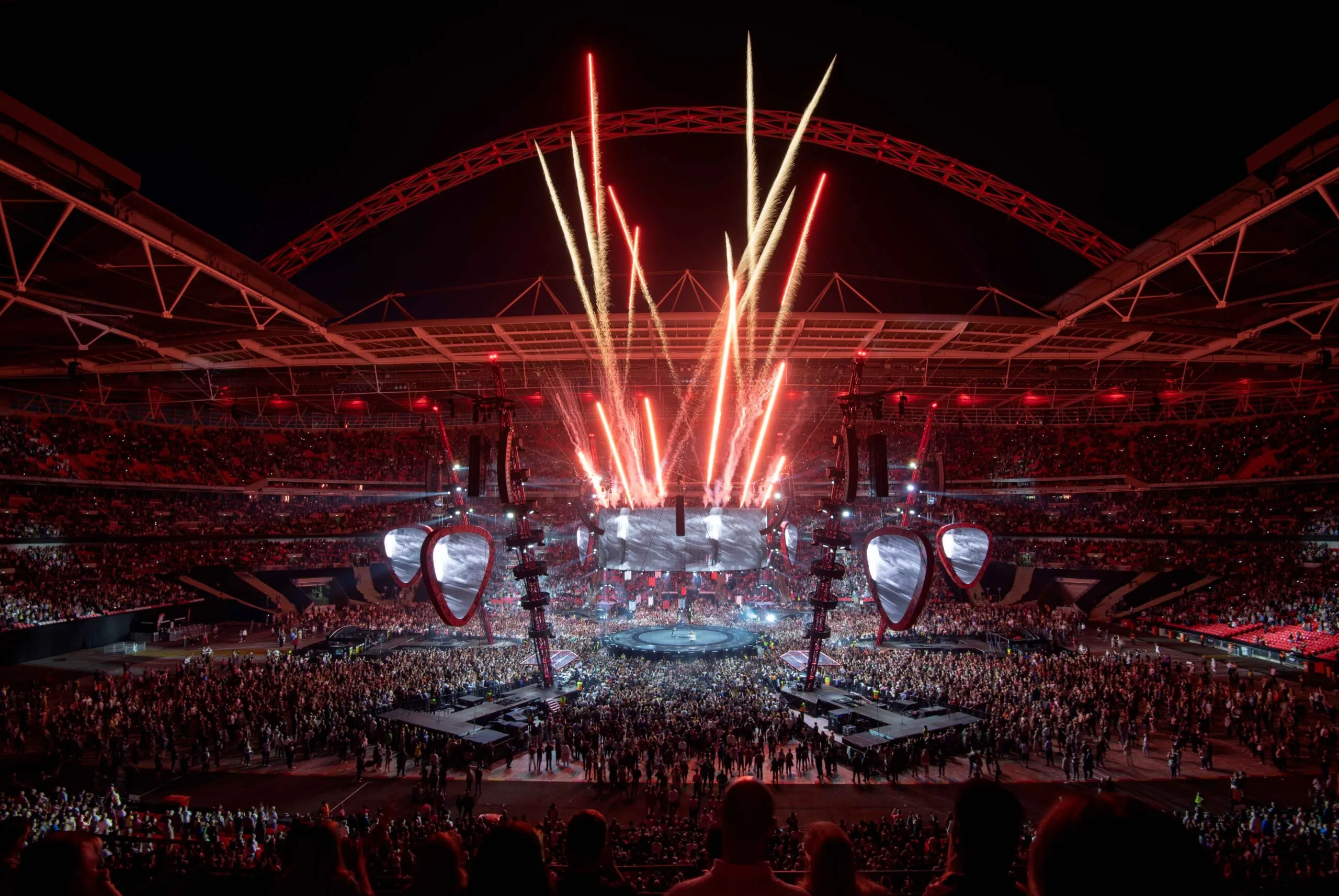 Wembley Stadium concerts | Venclikovi.com A wide-angle interior shot of a packed Wembley Stadium during a concert at night, featuring a massive stage, fireworks, and thousands of fans.